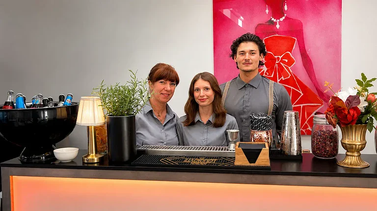 Drei Barkeeper hinter einer mobilen Bar bei einer Veranstaltung.